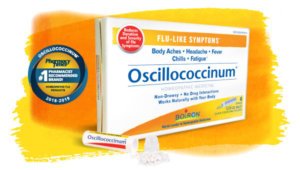Oscillococcinum box and tube with pellets spilled out, against yellow and orange watercolor background and Pharmacy Times award